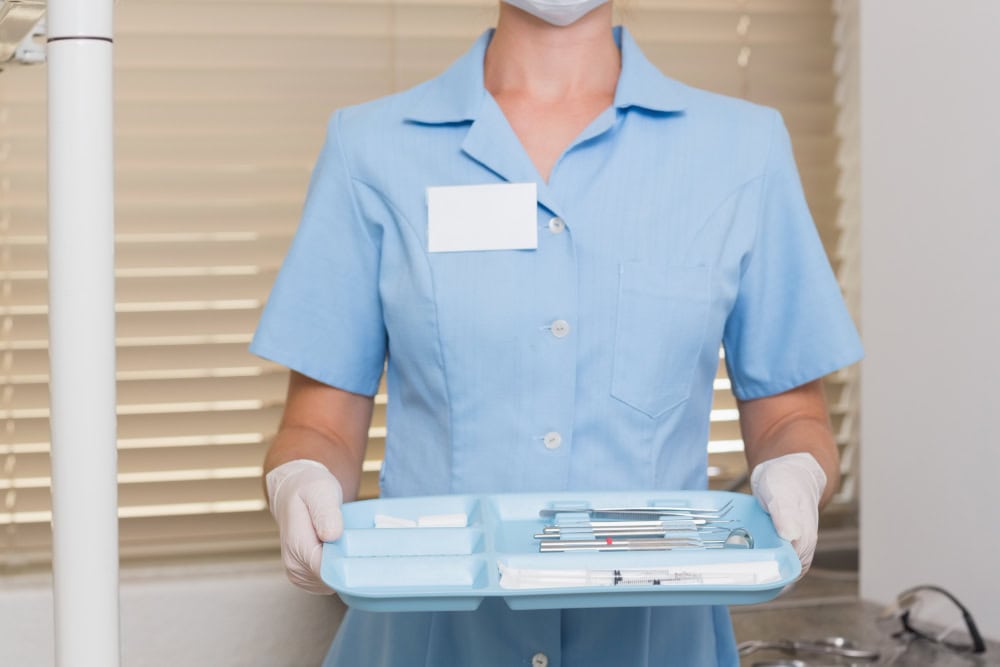Personal sanitario sosteniendo una bandeja azul con instrumental, mostrando un ejemplo de packaging farmacéutico para la organización de kits médicos.